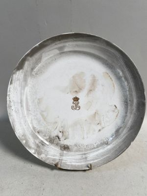 une assiette en argent ornée d'un emblème en or
