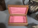 a small wooden box with a pink cloth inside of it