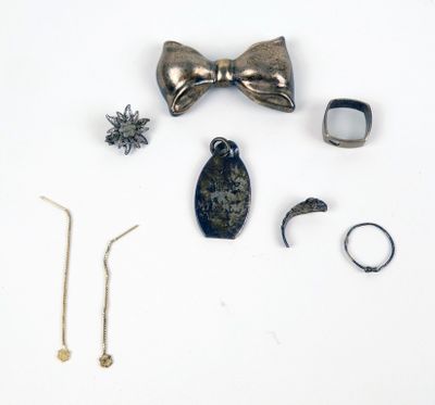 un nœud papillon, une bague, un bracelet et d'autres bijoux disposés sur une surface blanche