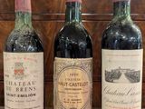 trois bouteilles de vin sont alignées sur une nappe rouge