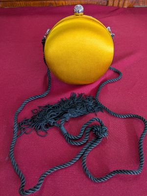 yellow purse on a red table cloth with a rope around it