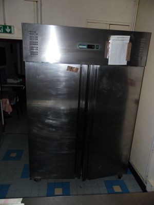 a stainless steel refrigerator in a room with a blue and white checkered floor