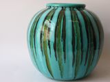 a blue vase with green stripes on it sitting on a table