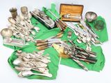 many different types of silverware on a green cloth