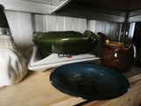 a blue bowl sitting on top of a wooden counter next to a green vase