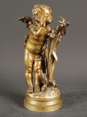 an antique bronze figurine of a cupid holding a bird