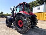 a red tractor that is parked in the dirt