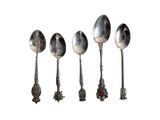 four silver spoons are lined up in a row on a white surface