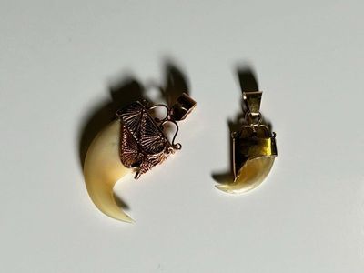 two pieces of jewelry sitting on a white surface