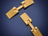 a pair of gold cufflinks on a blue background