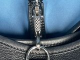 the zipper of a black leather purse with a silver metal clasp