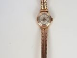 a close up of a gold wrist watch on a white surface