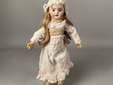 an antique porcelain doll of a woman in a white dress and hat