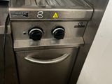 une cuisinière argentée sur laquelle sont posés une friteuse et un grille-pain