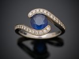un gros plan d'une bague en saphir et diamants posée sur une surface noire