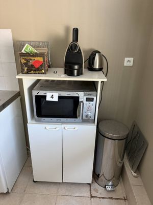 une petite cuisine équipée d'un micro-ondes, d'un réfrigérateur et d'une poubelle