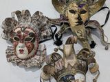 three different colored masks on a white surface with a black ribbon