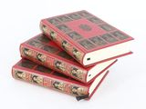 trois livres rouges empilés les uns sur les autres sur une surface blanche