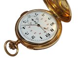 a gold pocket watch sitting on a white surface