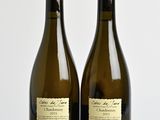 two bottles of wine sitting on top of a wooden table next to each other