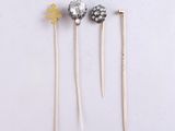 three silver and gold hair pins sitting on top of a white surface