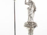 une statue représentant une femme tenant un verre et une canne