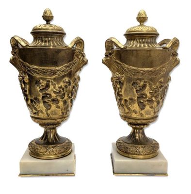 une paire de vases anciens en laiton posés sur des socles en marbre, sur fond blanc