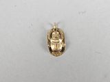 an image of a gold beetle charm on a white surface