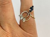 a woman ' s hand holding a ring with a diamond and a sapphire
