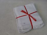 several folded white napkins tied with red ribbon on a table