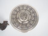 a small bird standing next to a silver plate on a table