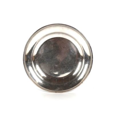 une assiette ancienne en argent, ornée d'un motif circulaire sur fond blanc