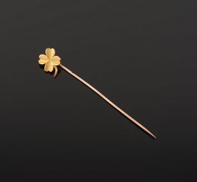a gold flower on a stick against a black background