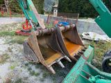 a green excavator that is sitting in the dirt