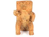 une petite statue représentant un ours assis sur une chaise