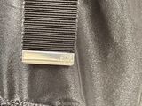 the back of a black jacket with a metal buckle on it
