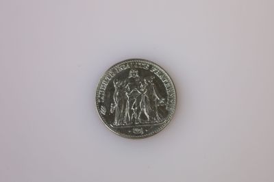 une pièce d'argent posée sur une surface blanche, sur fond blanc