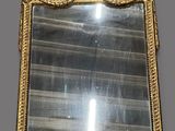 an ornate gold framed mirror hanging on a wall in a room