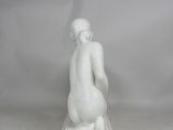 white marble statue of a woman kneeling on a marble base