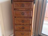 une haute commode en bois dans le coin d'une pièce
