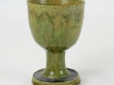 a green cup sitting on top of a white table