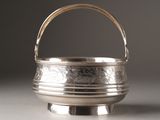 a small silver bowl with a handle on a table