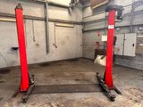 une photo d'un garage dans lequel se trouvent deux ponts élévateurs rouges