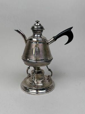 an antique silver teapot with a black handle on a stand