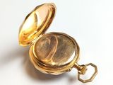 a gold pocket watch sitting on a white surface