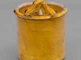 an old yellow pot with a handle on a gray surface