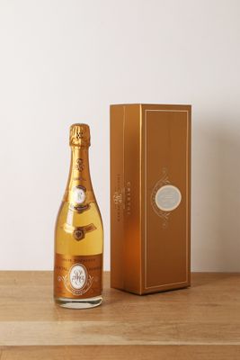 une photo montrant une bouteille de champagne posée à côté d'une boîte sur une table en bois