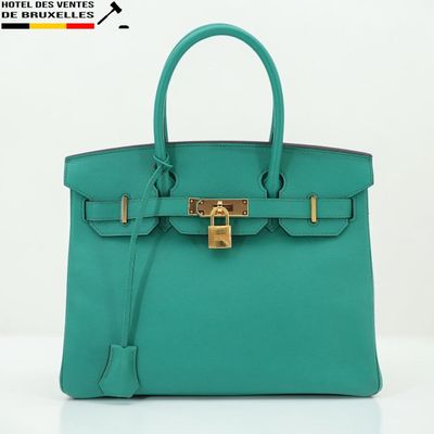 un sac à main en cuir vert muni d'un fermoir doré sur la poignée