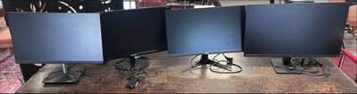 three computer monitors sitting on top of a wooden table