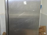 a silver refrigerator in the corner of a room with boxes on the floor
